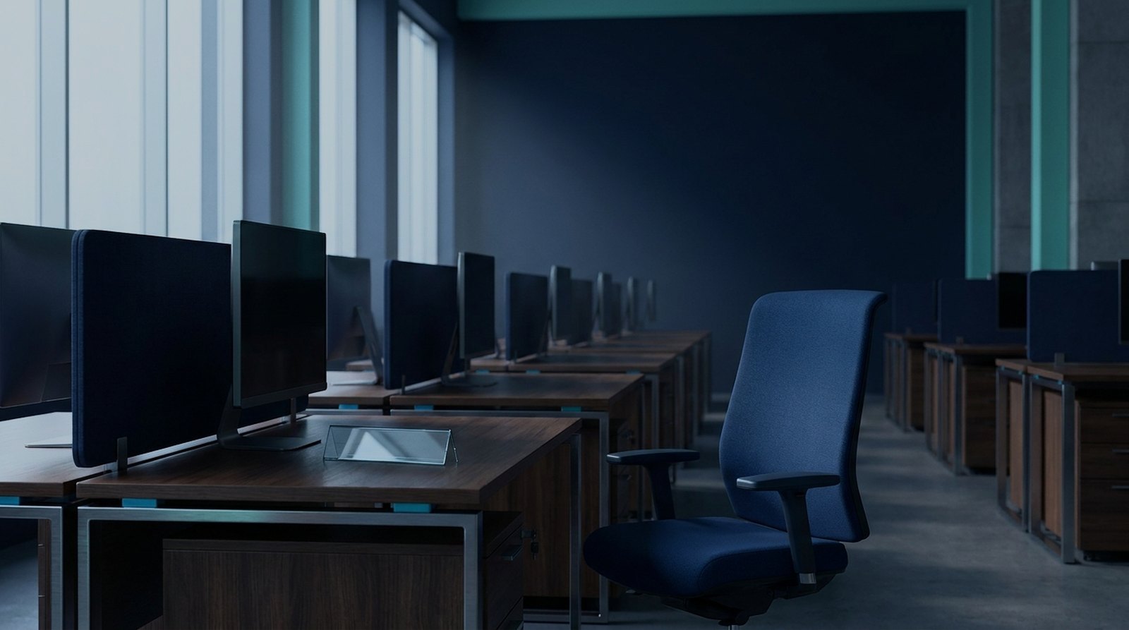 Row of empty call centre desks in cold morning light with one chair turned away